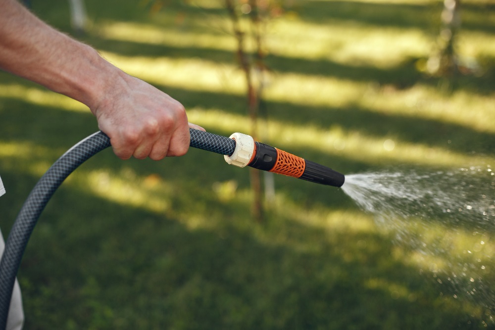 Muž zalévá zahradu dešťovou vodou.